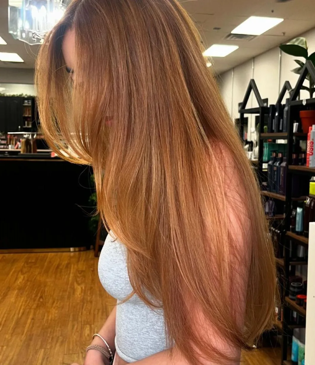 Long copper hair with face-framing layers and curtain bangs